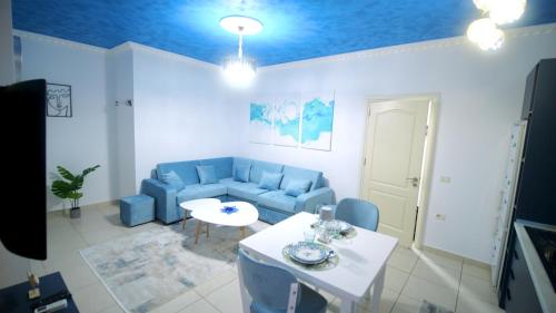 a living room with a blue couch and a table at Marina Apartment - The Ocean Heart of Shkodra in Shkodër