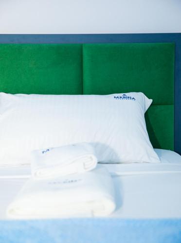 a white bed with a green headboard and white pillows at Marina Apartment - The Ocean Heart of Shkodra in Shkodër