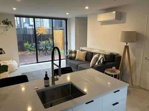 a kitchen and living room with a sink and a couch at Luxury 2 Bedroom Hideout Near CBD,Merivale Mall in Christchurch
