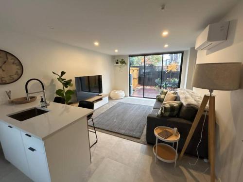 a kitchen and living room with a couch and a tv at Luxury 2 Bedroom Hideout Near CBD,Merivale Mall in Christchurch