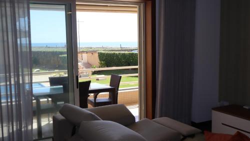 a living room with a couch and a sliding glass door at Pool and sea view accommodation 50 m sea in Furadouro