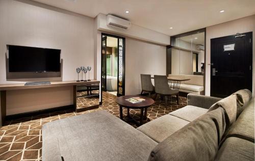 a living room with a couch and a tv and a table at Swiss-Belinn Tunjungan Surabaya in Surabaya