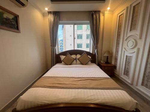 a bedroom with a large bed with a window at Madella Hotel in Can Tho