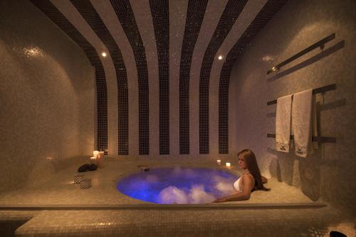 une femme assise dans une baignoire dans une salle de bains dans l'établissement Aressana Spa Hotel & Suites - Small Luxury Hotels of the World, à Fira