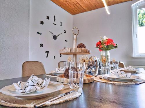 a dining room table with a clock on the wall at Ferien im Fachwerkhaus mit Heimkino & Fitnessraum & Pools in Burgwedel