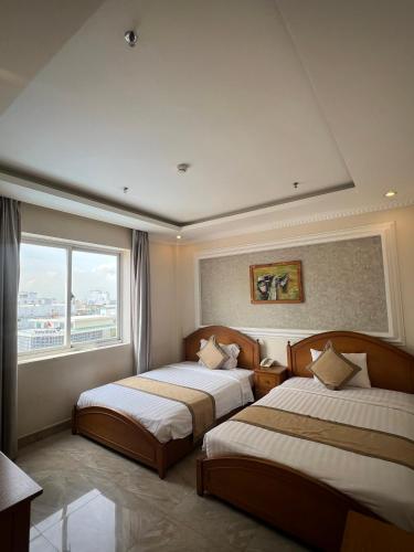 a hotel room with two beds and a window at Madella Hotel in Can Tho