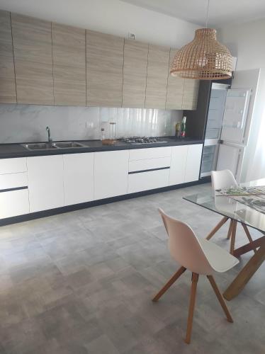 een keuken met witte kasten en een glazen tafel bij B&B Esotica in San Giovanni Teatino