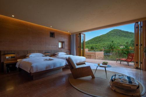 a bedroom with two beds and a view of a mountain at Linden Centre Shaxi in Diannan