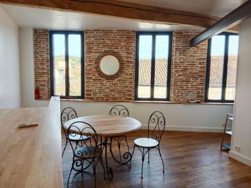 une pièce avec une table et des chaises et un mur de briques dans l'établissement Maison de village climatisée tout confort, à Grisolles