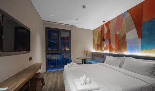 a bedroom with a large white bed and a tv at TK Phu Quoc Hotel - Grand World Phu Quoc in Phu Quoc