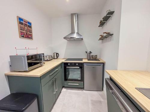 une cuisine avec une cuisinière et un micro-ondes dans l'établissement Le Turenne à 400 m de la plage, à Dunkerque