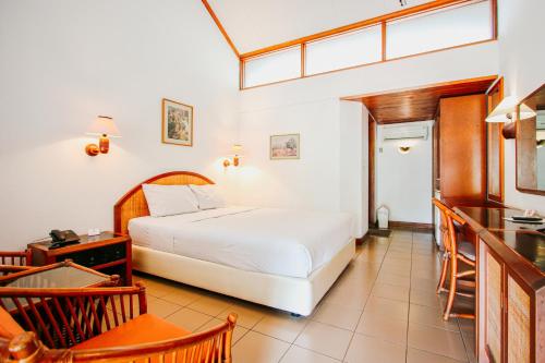 a bedroom with a bed and a table and chairs at Hotel Bumi Asih Gedung Sate Bandung in Bandung