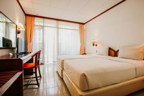 a hotel room with a bed and a desk and a television at Hotel Bumi Asih Gedung Sate Bandung in Bandung