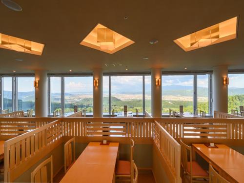 a restaurant with wooden benches and tables and windows at Shin Furano Prince Hotel in Furano