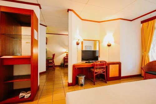 a hotel room with a desk and a television at Hotel Bumi Asih Gedung Sate Bandung in Bandung