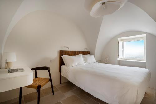 Un dormitorio con una cama y un escritorio y una ventana. en Casa u Bùrie, casa design con terrazza panoramica e jacuzzi, en Cisternino