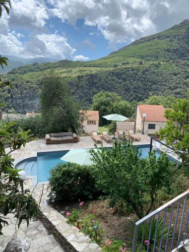 une villa avec une piscine et des montagnes en arrière-plan dans l'établissement À casa nostra, à Santo-Pietro-di-Tenda