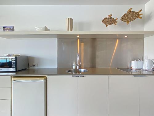 a kitchen with white cabinets and a sink at Blue on Blue Apartment 1361 in Nelly Bay