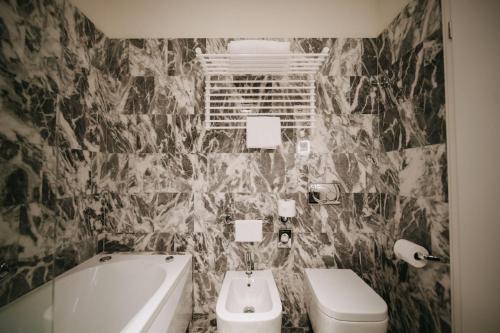 a bathroom with a tub and a toilet and a sink at Hotel Vis à Vis in Trieste