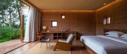 a bedroom with a bed and a desk and a window at Linden Centre Shaxi in Diannan