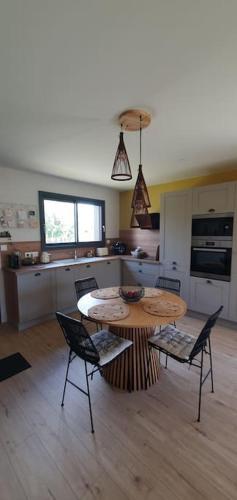 une cuisine avec une table et des chaises dans une pièce dans l'établissement Maison de plage Manoga, à Saint-Germain-sur-Ay