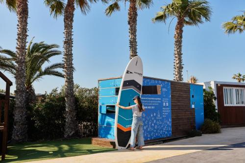 a woman holding a surfboard in front of a building at TAIGA Delta de l'Ebre in L'Ampolla
