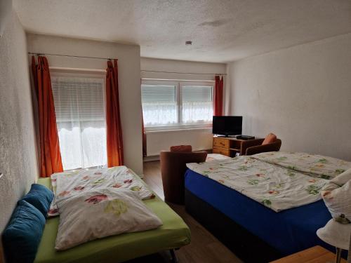 a bedroom with two beds and a television in it at Pension Arbersonne in Bayerisch Eisenstein