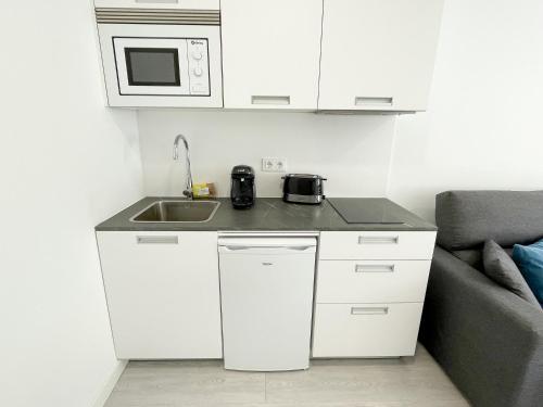 a kitchen with a sink and a microwave at Apartamentos Casa Campaña 3000 in O Grove