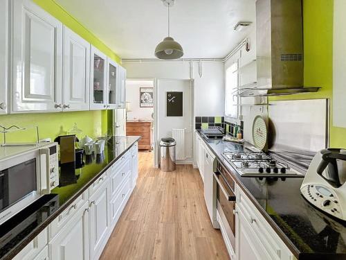 une grande cuisine avec des placards blancs et des murs verts dans l'établissement La Maison des Fées - 6 pers - 12 min de Compiègne, à Choisy-au-Bac