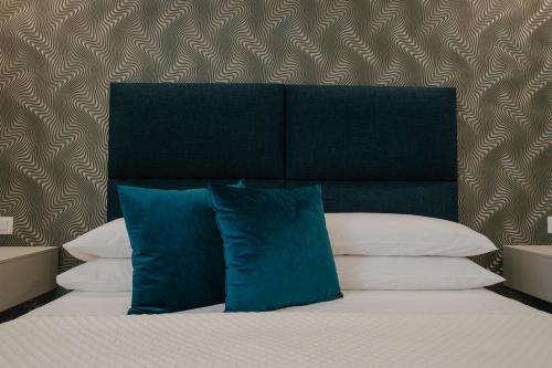 a bed with blue pillows and a black headboard at Marcone Luxury Rooms - Il giardino di pietra in Trani