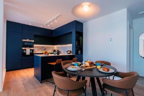 a kitchen with blue cabinets and a table and chairs at Media Bay Apartments in Kirchberg by Rentaroo in Luxembourg