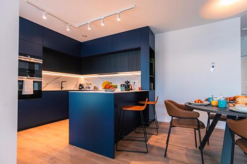 a kitchen with blue cabinets and a table with chairs at Media Bay Apartments in Kirchberg by Rentaroo in Luxembourg