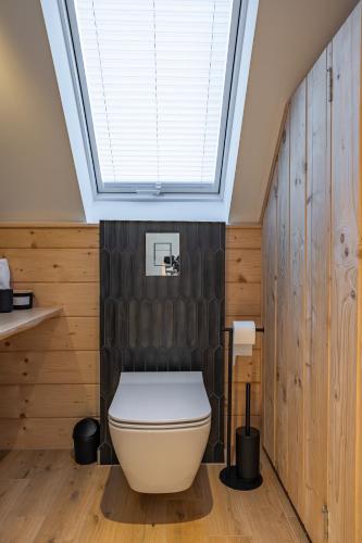 a bathroom with a toilet and a skylight at Osada Przystanek Czorsztyn in Czorsztyn