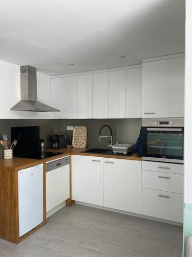 une cuisine avec des armoires blanches et un évier dans l'établissement L'Oranger, à Beg-Meil