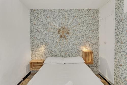1 dormitorio con cama y pared con papel pintado en Apartamento Con Encanto, en Maspalomas