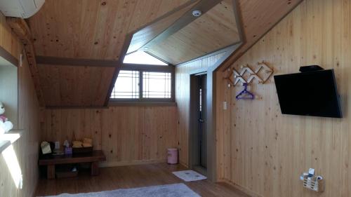 an attic room with a skylight and a television on the wall at Bangdigareum B&B in Seogwipo