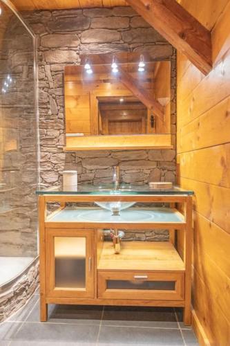 une salle de bain avec un lavabo et un mur en pierre dans l'établissement Le Refuge de Louis, authentique grange rénovée avec sauna, à Ventron