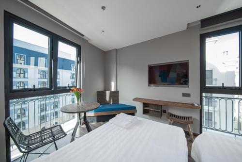a bedroom with a bed and a table and some windows at TK Phu Quoc Hotel - Grand World Phu Quoc in Phu Quoc