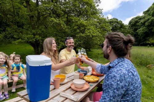 a group of people sitting at a picnic table with wine glasses at River Fishing I Hot tub I Games Room I PetFriendly in Rainow