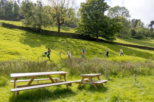 a group of people walking in a field with benches at River Fishing I Hot tub I Games Room I PetFriendly in Rainow