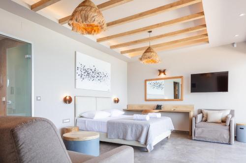 a bedroom with a bed and a couch and a tv at Skipper Beachfront Suites in Hersonissos