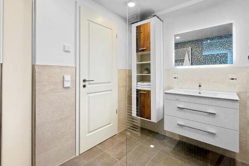 Un baño blanco con lavabo y espejo. en Penthouse Hafenkieker, en Putbus