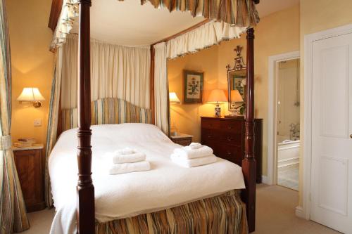 a bedroom with a canopy bed with towels on it at Sandown Cottage in Bruern