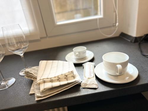 a table with plates and cups and a glass of wine at Como Charme Apartment in Como