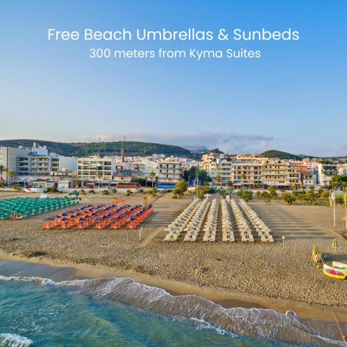 a beach with beach umbrellas and chairs and buildings at Kyma Suites Beach Hotel in Rethymno Town