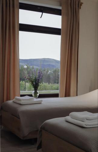 a bedroom with two beds and a window with a vase of flowers at Sevan - Artanish Beach Resort in Artanish