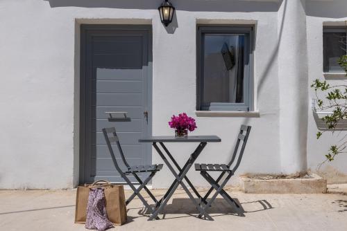 a table and two chairs in front of a door at Chrysonisos Suites with Sunset & Seaviews near Kini in Ano Syros