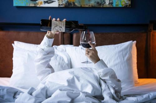 a woman laying in bed with a glass of wine at Hotel Nell - Union Market in Washington