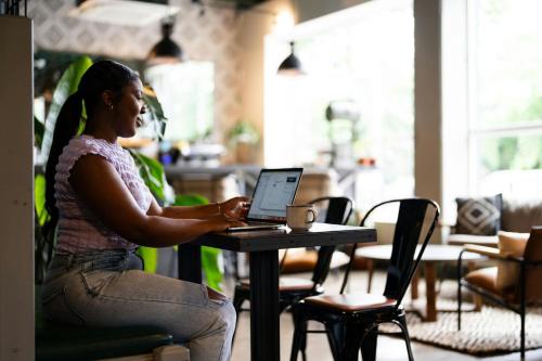 a woman sitting at a table with a laptop computer at Hotel Nell - Union Market in Washington