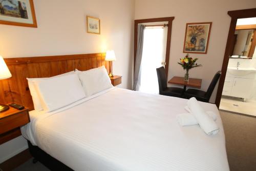 a bedroom with a large white bed with two pillows at Belgravia Mountain Guest House in Katoomba
